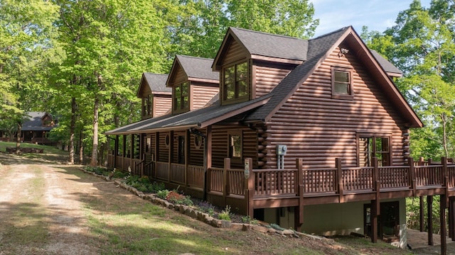 view of property exterior featuring a deck, log exterior, and roof with shingles