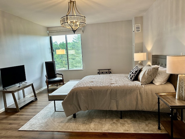 bedroom with baseboards, a chandelier, and wood finished floors