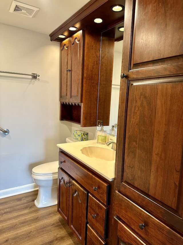 bathroom with visible vents, wood finished floors, vanity, baseboards, and toilet