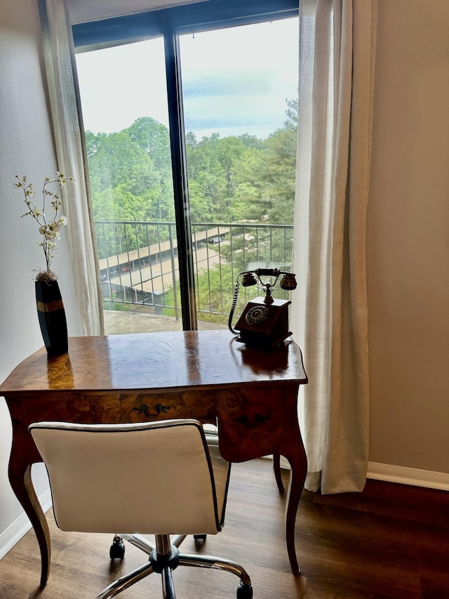 office with baseboards, wood finished floors, and a wooded view