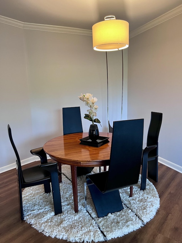 dining area featuring crown molding, baseboards, and wood finished floors
