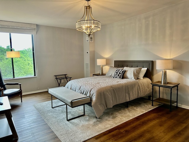 bedroom with baseboards, a notable chandelier, and dark wood-style floors