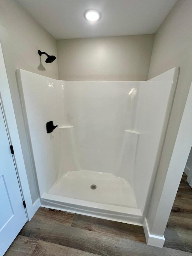 full bathroom featuring walk in shower and wood finished floors
