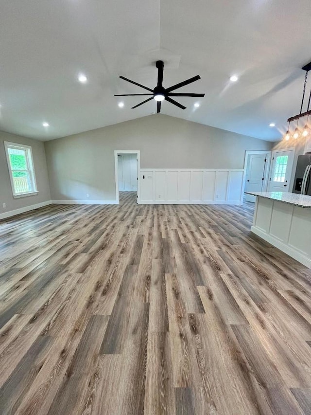 unfurnished living room featuring wood finished floors, recessed lighting, a wainscoted wall, a ceiling fan, and vaulted ceiling