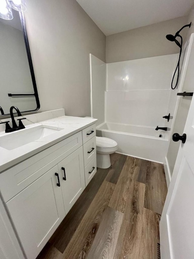 full bathroom with vanity, bathtub / shower combination, toilet, and wood finished floors