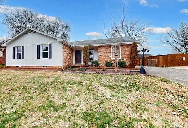 single story home featuring brick siding, fence, driveway, and a front yard