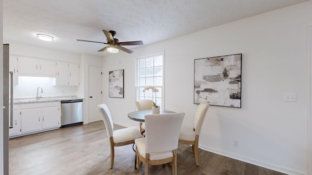 dining room with a textured ceiling, ceiling fan, baseboards, and light wood-style floors