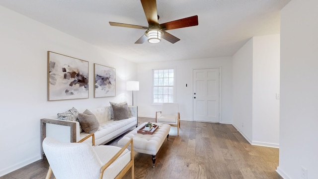 living room featuring light wood-style floors, baseboards, and ceiling fan