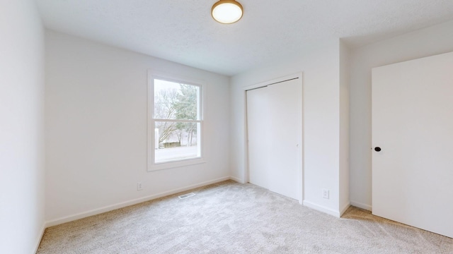 unfurnished bedroom featuring carpet flooring, visible vents, and a closet