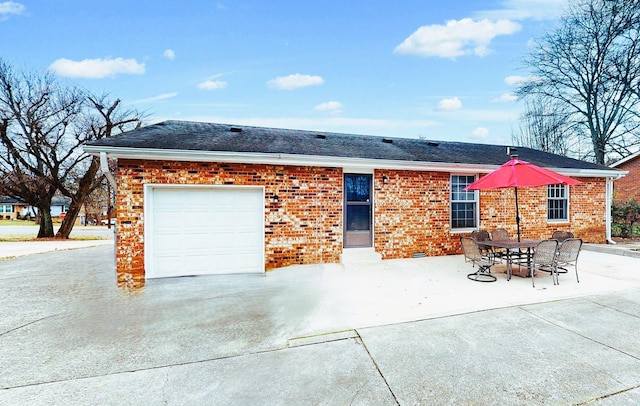 back of property featuring roof with shingles, a garage, driveway, and brick siding