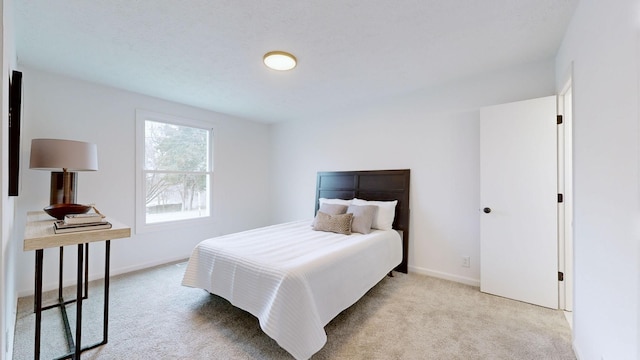 bedroom with baseboards and light carpet
