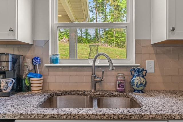 interior details featuring a sink, decorative backsplash, and white cabinetry