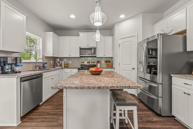 kitchen featuring appliances with stainless steel finishes, tasteful backsplash, a center island, a sink, and white cabinets