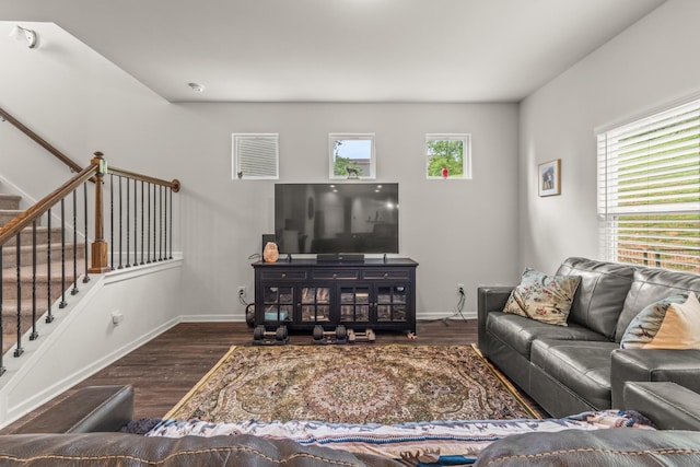 living room featuring baseboards, wood finished floors, a healthy amount of sunlight, and stairway