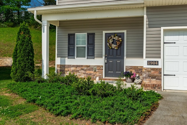 property entrance featuring covered porch, stone siding, and concrete driveway