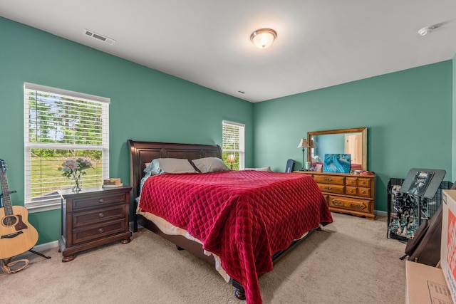 carpeted bedroom with visible vents, baseboards, and multiple windows