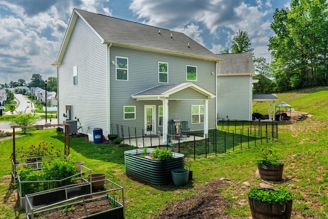 rear view of property featuring a lawn, central AC unit, a garden, and a patio