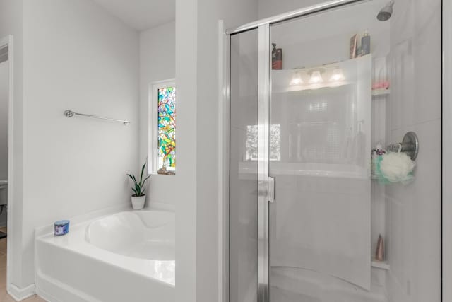 full bathroom featuring a bath and a shower stall