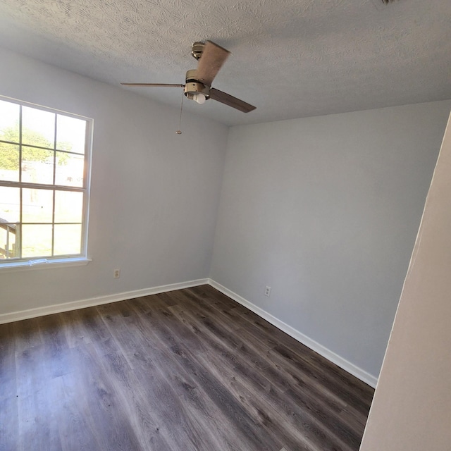 empty room with a textured ceiling, ceiling fan, baseboards, and dark wood-type flooring