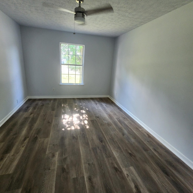 spare room featuring baseboards, a ceiling fan, dark wood-style flooring, and a textured ceiling
