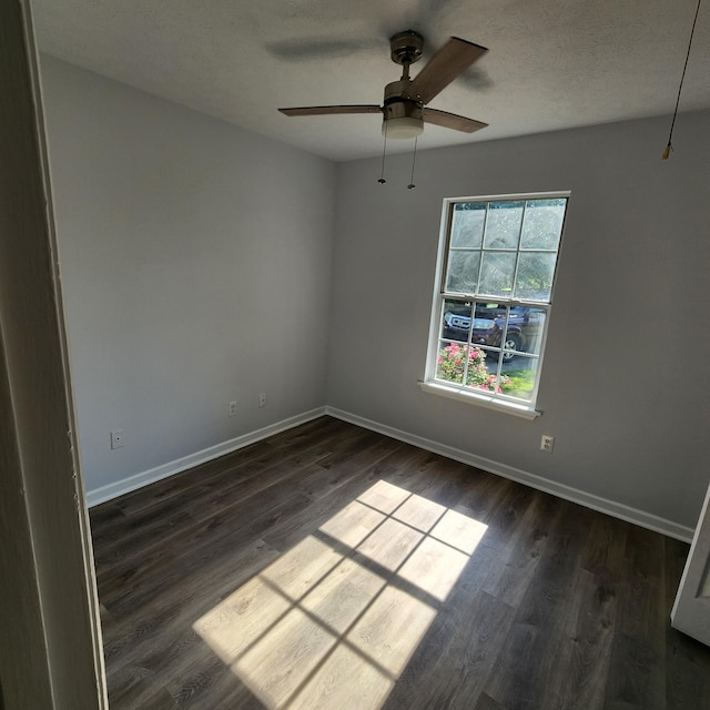 empty room with a ceiling fan, baseboards, and dark wood finished floors