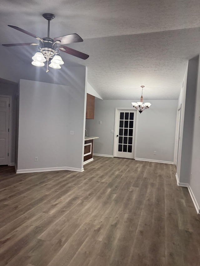 unfurnished living room with lofted ceiling, baseboards, a textured ceiling, dark wood finished floors, and ceiling fan with notable chandelier