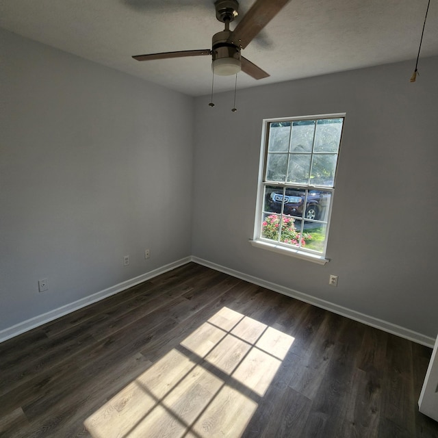 empty room featuring dark wood-type flooring, baseboards, and ceiling fan