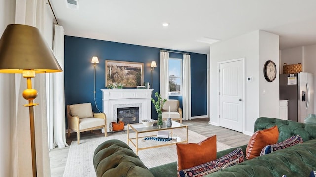 living room with a fireplace, recessed lighting, baseboards, wood finished floors, and visible vents