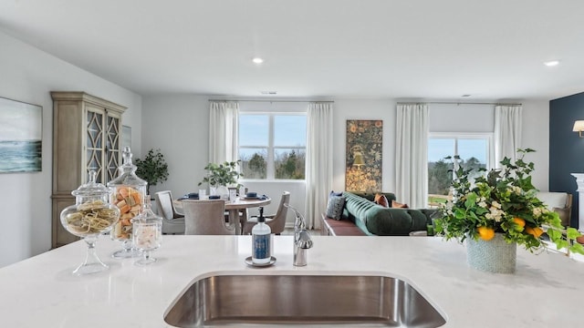 kitchen featuring light countertops, open floor plan, plenty of natural light, and a sink