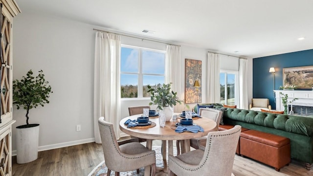 dining space featuring a fireplace, baseboards, visible vents, and light wood-type flooring
