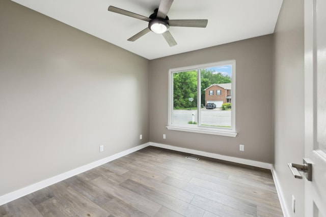 empty room with a ceiling fan, baseboards, visible vents, and wood finished floors