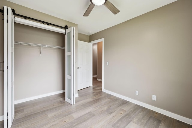unfurnished bedroom featuring baseboards, a ceiling fan, a closet, and light wood-type flooring