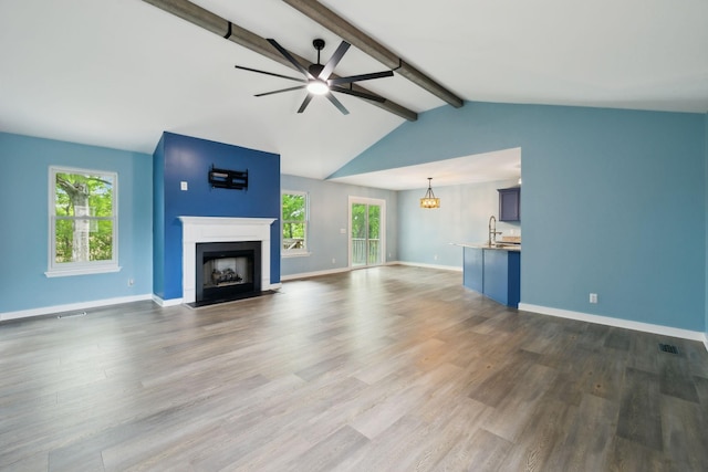 unfurnished living room featuring baseboards, a sink, a fireplace with flush hearth, and ceiling fan with notable chandelier