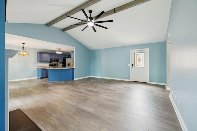unfurnished living room with lofted ceiling with beams, a sink, ceiling fan with notable chandelier, baseboards, and wood finished floors