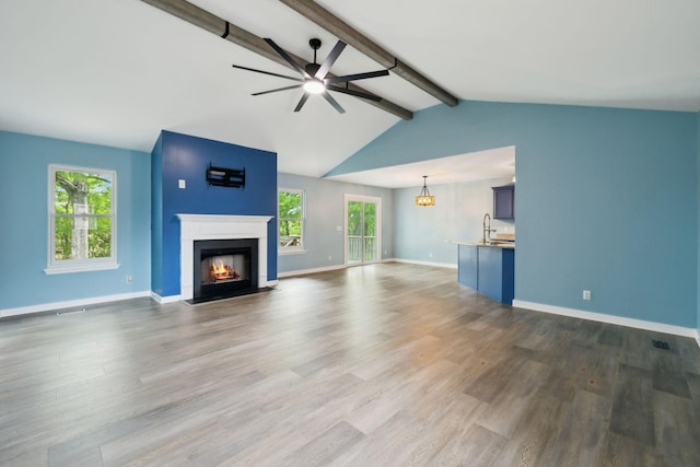 unfurnished living room featuring a fireplace with flush hearth, dark wood finished floors, a sink, baseboards, and ceiling fan with notable chandelier