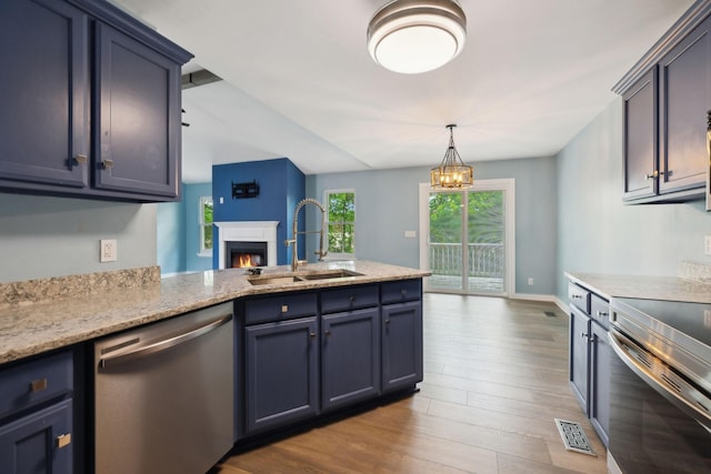 kitchen featuring appliances with stainless steel finishes, a sink, visible vents, dark wood-type flooring, and a lit fireplace