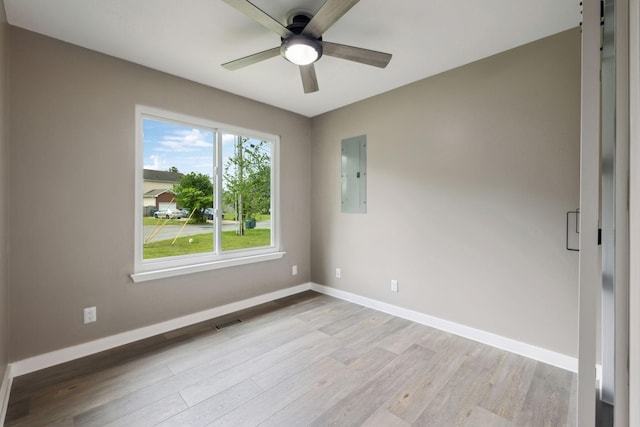 spare room with ceiling fan, electric panel, visible vents, baseboards, and light wood-style floors