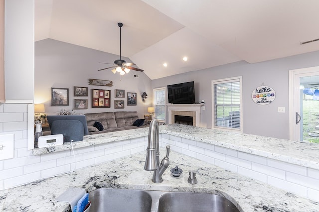 1137 Stillwood Dr, Clarksville, TN 37042 - kitchen with a sink, lofted ceiling, a ceiling fan, a tiled fireplace, and light stone countertops