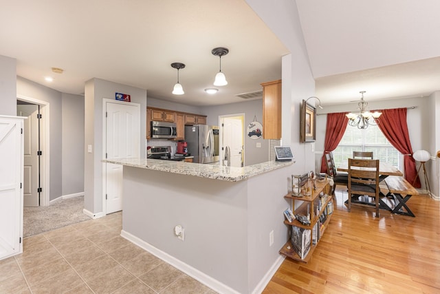 1137 Stillwood Dr, Clarksville, TN 37042 - kitchen featuring stainless steel appliances, a chandelier, baseboards, brown cabinetry, and hanging light fixtures