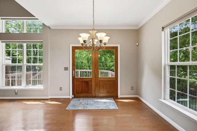 entryway with crown molding, a chandelier, baseboards, wood finished floors, and visible vents