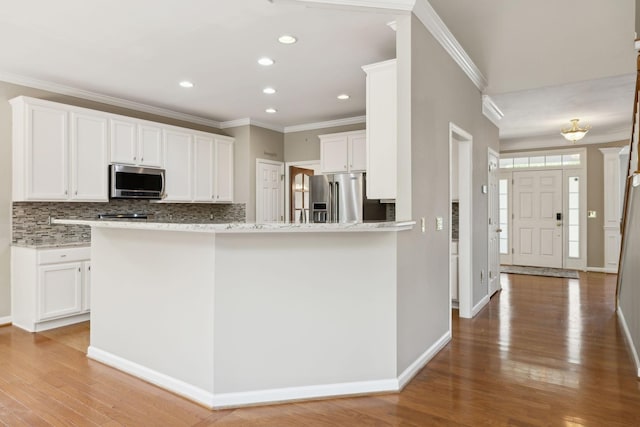 kitchen featuring crown molding, backsplash, appliances with stainless steel finishes, and light wood-style flooring