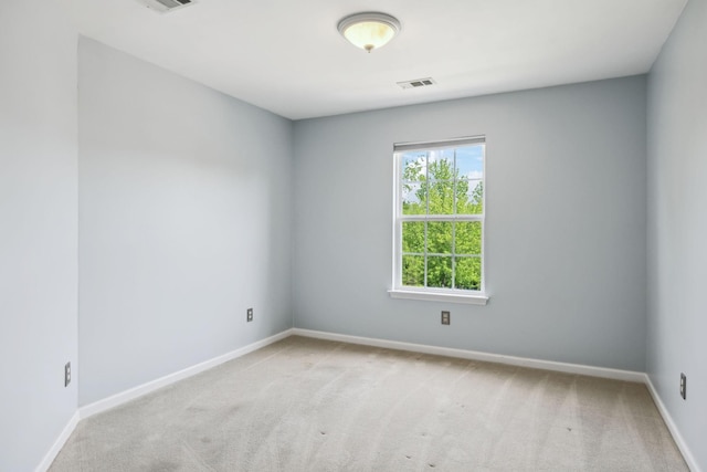 spare room featuring visible vents, baseboards, and light carpet