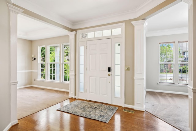 foyer entrance with ornamental molding, decorative columns, and carpet flooring