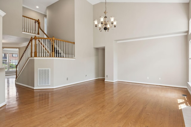 interior space with visible vents, stairs, a towering ceiling, wood finished floors, and a chandelier