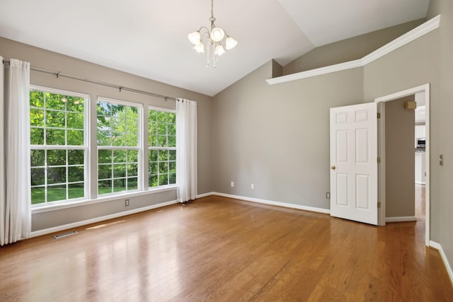 spare room featuring visible vents, vaulted ceiling, wood finished floors, baseboards, and a notable chandelier