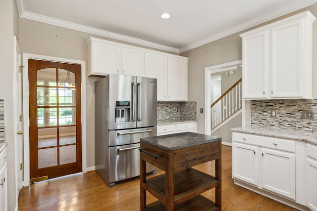 kitchen with white cabinetry, light wood finished floors, stainless steel fridge with ice dispenser, and tasteful backsplash