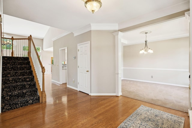 entrance foyer with wood finished floors, baseboards, an inviting chandelier, ornamental molding, and stairs