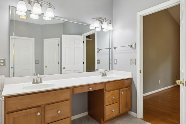 full bath with a sink, double vanity, and wood finished floors