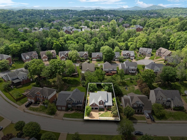 birds eye view of property with a wooded view, a mountain view, and a residential view
