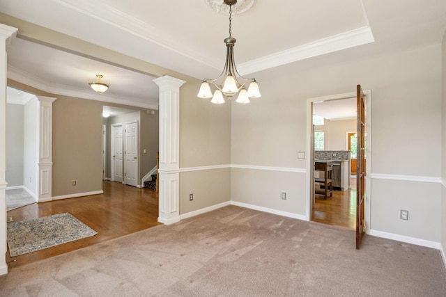 carpeted spare room featuring stairs, baseboards, a notable chandelier, ornamental molding, and ornate columns